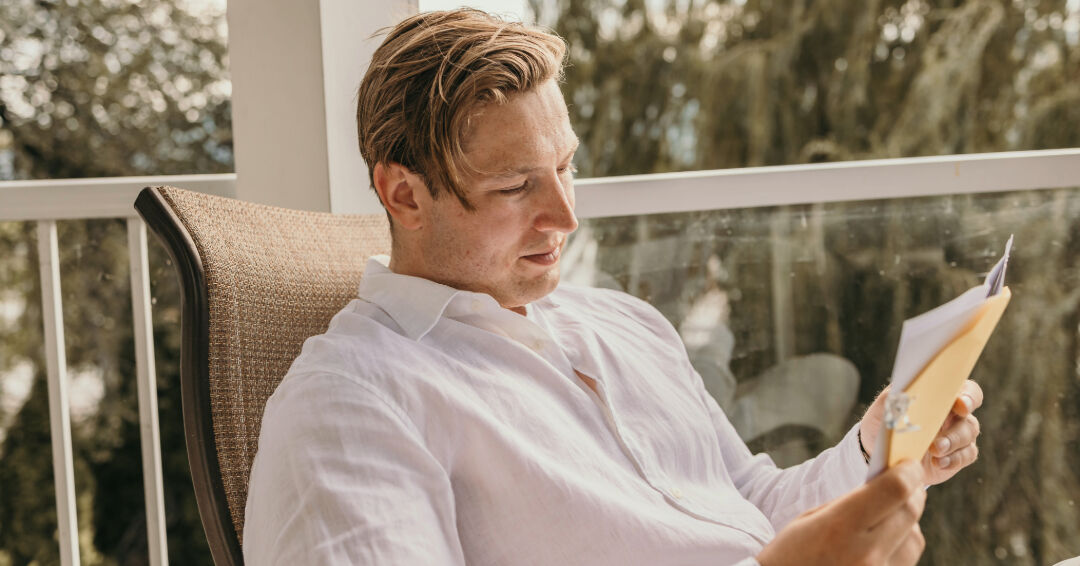 Groom reading a handwritten letter on a balcony before the ceremony